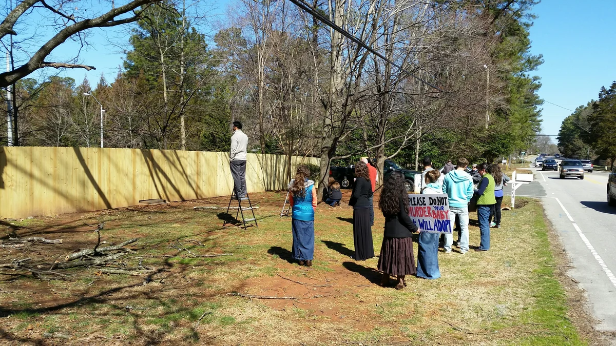 Pro-life demonstrators standing beside a newly erected fence outside an abortion clinic